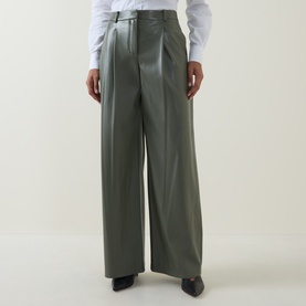 Model wearing Hugo Boss dark green faux leather wide-leg trousers with pleat front, styled with a white shirt and black heels.