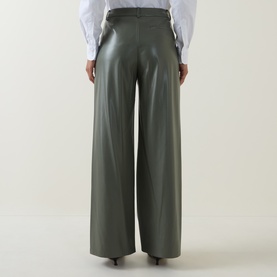 Model wearing Hugo Boss dark green wide-leg faux leather trousers, rear view, styled with a white blouse.