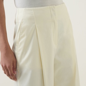 Model wearing Hugo Boss open beige wide-leg trousers with front pleat detail, cropped close-up view of hip and thigh area.