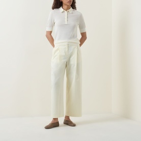 Model wearing Hugo Boss Open Beige wide-leg cotton trousers with a white knit polo shirt and taupe loafers.