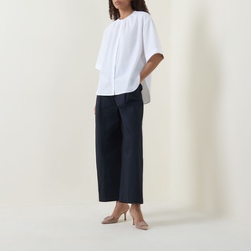 Model wearing Hugo Boss dark blue wide-leg cotton trousers, styled with a white short-sleeve top and nude heels.