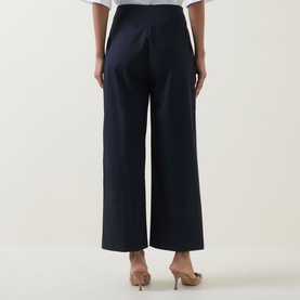 Model wearing Hugo Boss dark blue wide-leg trousers, rear view, styled with a white top and nude heeled mules.