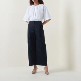 Model wearing Hugo Boss dark blue wide-leg culottes, styled with a white short-sleeve blouse and nude heels.