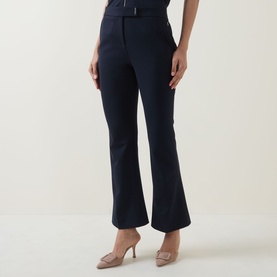 Model wearing Hugo Boss Talia-Crop1 Mid-Rise Flared Trousers in dark blue with pressed creases and logo tab waist, styled with nude heels