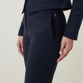 Model wearing Hugo Boss Talia-Crop1 Mid-Rise Flared Trousers in dark blue with pressed creases and logo plate waistband, styled with matching blazer.