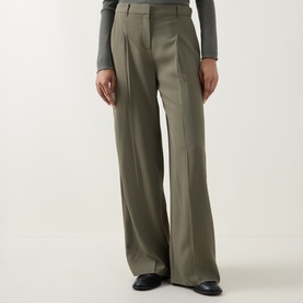 Model wearing Hugo Boss wide-leg tailored trousers in khaki green with front pleats, styled with a grey top and black loafers.