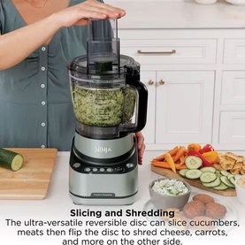 Ninja PrecisionPro Food Processor in silver processing vegetables, with reversible disc for slicing and shredding, shown in kitchen setting
