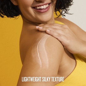 Sol De Janeiro body lotion applied to model's shoulder, showing lightweight silky texture streaks on skin against yellow background