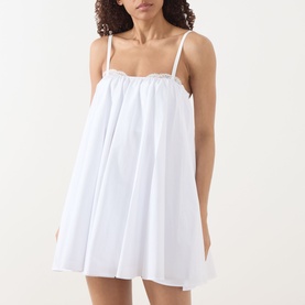 Model wearing Staud Cecily Flared Mini Dress in white, with lace-trim square neckline, spaghetti straps and flared skirt