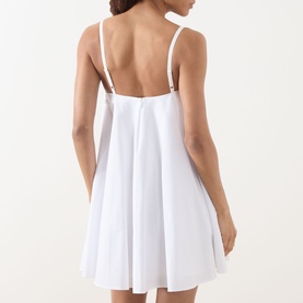 Model wearing Staud Cecily Flared Mini Dress in white, rear view showing open back with spaghetti straps and flared hemline.