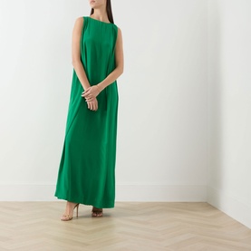 Model wearing Staud kelly green silk maxi dress with sleeveless design and draped back detail, styled with nude heeled sandals and white bangles