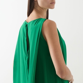 Model wearing Staud dress in kelly green, showing open-back detail with central tie, relaxed silk silhouette, side-on view