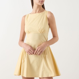 Model wearing Staud butter yellow mini dress with fitted bodice, cinched waist, and full pleated skirt in cotton fabric