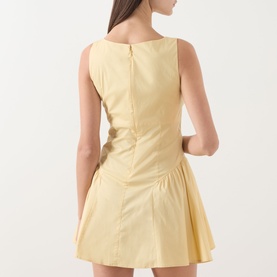 Model wearing Staud butter yellow sleeveless mini dress with fitted bodice, ruched detail, and flared skirt, shown from the back.