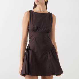 Model wearing Staud earth brown mini dress with fitted bodice, ruched bust detail, sleeveless cut and flared pleated skirt