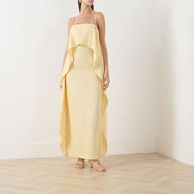 Model wearing Staud Valencia Ruffle Dress in butter yellow linen, maxi length with spaghetti straps and draped ruffle overlay, styled with nude