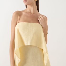 Model wearing Staud Valencia Ruffle Dress in butter yellow linen, with spaghetti straps and ruffle detail. Styled with gold jewellery.
