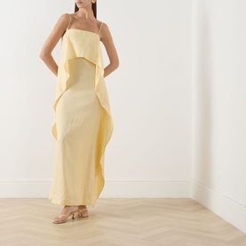 Model wearing Staud Valencia Ruffle Dress in butter yellow linen, maxi length with column silhouette, ruffle detail and spaghetti straps, styled with