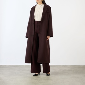 Model wearing Victoria Beckham Elderflower blouse styled with dark burgundy longline coat and wide-leg trousers, black heels