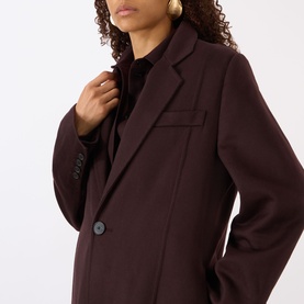 Model wearing Victoria Beckham Single-Breasted Coat in Acai with notched lapels and button fastening, styled with gold hoop earrings.