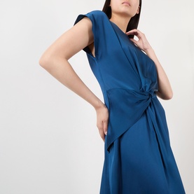 Model wearing Victoria Beckham Aria Twist Waist Dress in Dark Ocean, featuring cap sleeves, front twist waist detail and flared asymmetric midi hem
