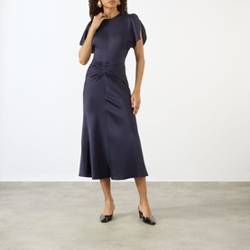 Model wearing Victoria Beckham Midnight dress with flutter sleeves, ruched waist detail, and midi flared skirt, styled with black ballet flats