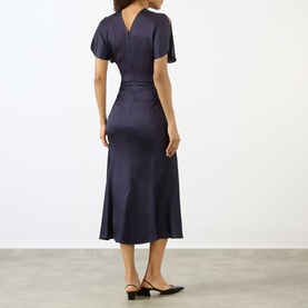 Model wearing Victoria Beckham Midnight satin midi dress with short sleeves and fitted silhouette, shown from back, styled with black kitten heel