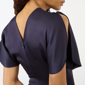 Model wearing Victoria Beckham Midnight dress, close-up of open back detail with zip fastening and short flutter sleeves.