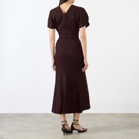 Model wearing Victoria Beckham Dress in Acai, back view showing V-neckline, short sleeves, and midi flared skirt, styled with black strappy heels