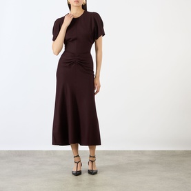 Model wearing Victoria Beckham Acai midi dress with short puff sleeves and ruched waist detail, styled with black heels