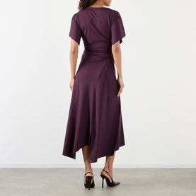 Model wearing Victoria Beckham Gathered Asymmetric Dress in Blackcurrent, rear view, asymmetric midi hem, short sleeves, styled with black heels