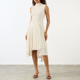 Model wearing Victoria Beckham Pleated Asymmetric Dress in Elderflower, sleeveless with high neck, midi length and asymmetric pleated hem