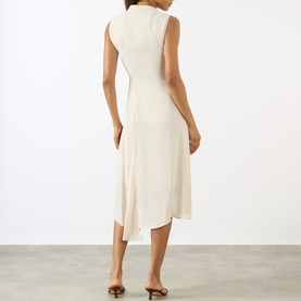 Model wearing Victoria Beckham Pleated Asymmetric Dress in Elderflower, sleeveless midi with asymmetric hemline, styled with tan heeled mules.