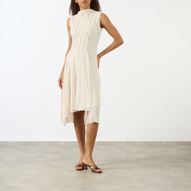 Model wearing Victoria Beckham Pleated Asymmetric Dress in Elderflower with high neck, sleeveless bodice and asymmetric pleated midi hem, styled with