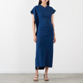 Model wearing Victoria Beckham Dark Ocean blue midi dress with V-neckline, cap sleeves and ruched waist detail, styled with strappy heeled sandals.