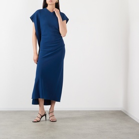 Model wearing Victoria Beckham Dark Ocean blue midi dress with cap sleeves and ruched side detail, styled with black strappy heeled sandals.