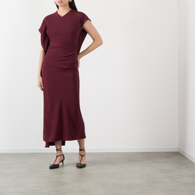 Model wearing Victoria Beckham Victoria Draped Dress in Cinnabar Red with asymmetric neckline, draped midi silhouette, styled with black heels.