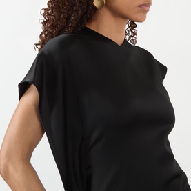 Model wearing Victoria Beckham black satin-finish dress with cap sleeves and draped neckline, styled with gold drop earrings.