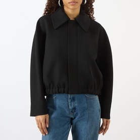 Model wearing Victoria Beckham black cropped jacket with wide collar and zip front, styled with blue jeans