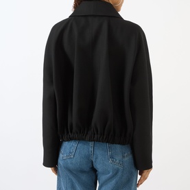 Model wearing Victoria Beckham black jacket, rear view, elasticated hem, worn with light blue jeans.