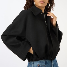 Model wearing Victoria Beckham black oversized jacket with zip collar, styled with light blue jeans