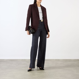 Model wearing Victoria Beckham Alina High-Rise Flared Leg Jeans in indigo, styled with a burgundy blazer, white tee, and black heels