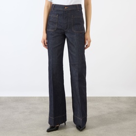 Model wearing Victoria Beckham Alina High-Rise Flared Leg Jeans in indigo with tobacco stitching and front patch pockets, styled with black heels