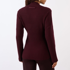 Model wearing burgundy ribbed knit turtleneck jumper, back view, styled with matching burgundy trousers