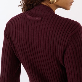 Model wearing a burgundy ribbed knit sweater, back view showing tonal logo patch at collar and structured ribbed detailing.