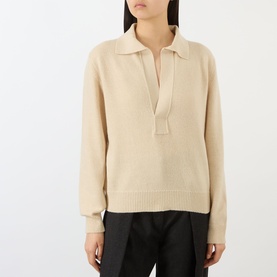 Model wearing Victoria Beckham knit polo in Elderflower, featuring open V-neck collar and ribbed hem, styled with dark trousers