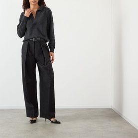 Model wearing Victoria Beckham Genevieve Knitted Polo Sweater in Ore Melange with wide-leg black trousers, belt and black heeled mules.