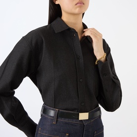 Model wearing black button-up shirt, styled with dark denim jeans, black belt with gold buckle, and gold bracelet watch