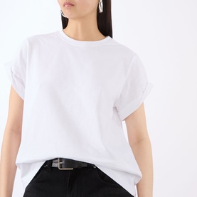 Model wearing Victoria Beckham white T-shirt with rolled sleeves and crew neck, styled with black belt and dark jeans