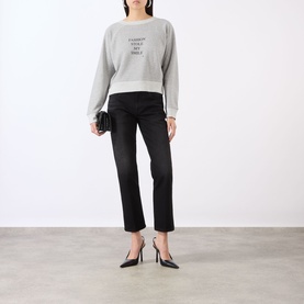 Model wearing Victoria Beckham Grey Marl Fashion slogan sweatshirt, styled with black straight-leg jeans, heels, and clutch bag.
